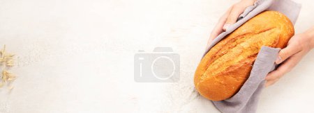 Téléchargez les photos : Boulanger ou chef cuisinier tenant du pain frais cuit dans les mains sur un fond clair. Concept de cuisine. Panorama. - en image libre de droit