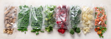 Téléchargez les photos : Ensemble de différents légumes congelés dans des sacs en plastique sur fond blanc. Vue de dessus. Panorama. - en image libre de droit