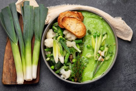 Téléchargez les photos : Soupe verte à la crème de légumes dans un bol gris sur fond gris, vue de dessus. Purée de légumes verts à la soupe végétalienne. Aliments végétariens et diététiques. - en image libre de droit