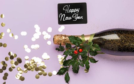 Téléchargez les photos : Bouteille de champagne avec confettis sur fond violet. Noel, anniversaire ou concept de mariage. Pose plate. - en image libre de droit