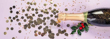 Foto de Botella de champán con confeti sobre fondo violeta. Concepto de Navidad, cumpleaños o boda. Acostado. Panorama. - Imagen libre de derechos