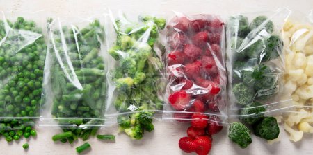 Foto de Conjunto de diferentes verduras congeladas en bolsas de plástico sobre fondo blanco. Vista superior. - Imagen libre de derechos