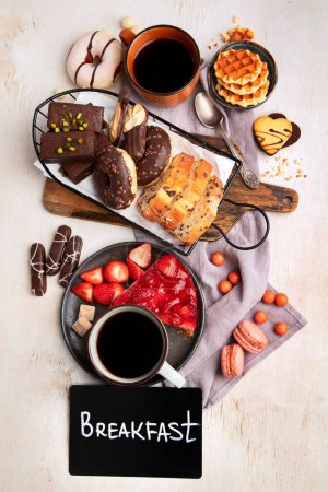 Téléchargez les photos : Tasse de café avec gaufres, biscuits, gâteaux et cacahuètes sur fond clair. Boissons chaudes et desserts. Vue du dessus. - en image libre de droit