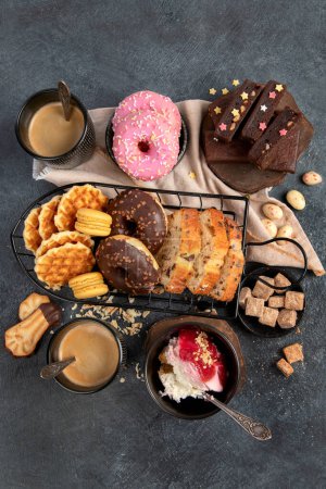 Photo for White coffee with delicious cookie, donuts, cake, sugar, waffles. Hot drink with sweets on dark background. Top view, copy space. - Royalty Free Image