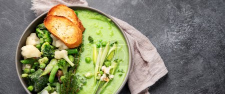 Téléchargez les photos : Soupe verte à la crème de légumes dans un bol gris sur fond gris, vue de dessus. Purée de légumes verts à la soupe végétalienne. Aliments végétariens et diététiques. Panorama avec espace de copie. - en image libre de droit
