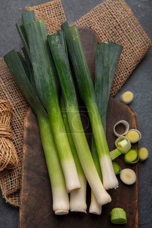 Photo for Whole and cut fresh leeks on a dark background, vegetarian food, healthy eating. Top view. - Royalty Free Image
