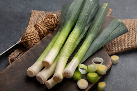 Photo for Whole and cut fresh leeks on a dark background, vegetarian food, healthy eating. Top view. - Royalty Free Image