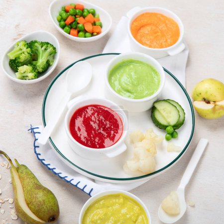 Téléchargez les photos : Nourriture pour bébé. Bol avec purée de fruits de légumes, vert, orange, jaune couleurs brocoli, carottes, banane, pomme. - en image libre de droit
