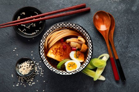 Téléchargez les photos : Soupe asiatique avec oeuf, tofu, champignons et oignon sur fond noir. Concept alimentaire traditionnel. Vue du dessus. - en image libre de droit
