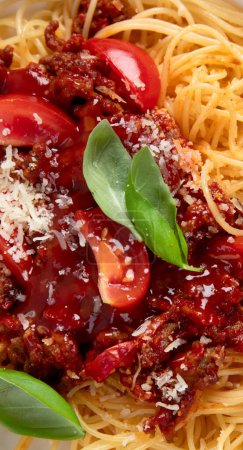Foto de Sabroso apetitoso clásico italiano spaghetti pasta boloñesa con salsa de tomate, queso parmesano, carne y albahaca en el plato sobre un fondo oscuro. Vista superior. - Imagen libre de derechos