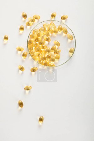 Foto de Placa de Petri con cápsulas de aceite de pescado en ella. Concepto de vitamina d, vitaminas omega sobre un fondo blanco. Vista superior. - Imagen libre de derechos