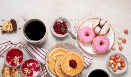 Foto de Mesa con varias galletas americanas, rosquillas, tortitas y tazas de café en fondo blanco. Vista superior. Copiar espacio. - Imagen libre de derechos