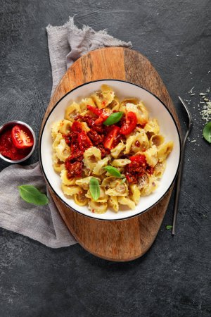 Photo for Traditional italian food. Dish with ravioli, tomato, Sun-dried tomatoes, basics and grated cheese. Tasty pasta. Top view - Royalty Free Image