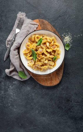 Photo for Traditional italian food. Dish with ravioli, tomato, Sun-dried tomatoes, basics and grated cheese. Tasty pasta. Top view, copy space - Royalty Free Image