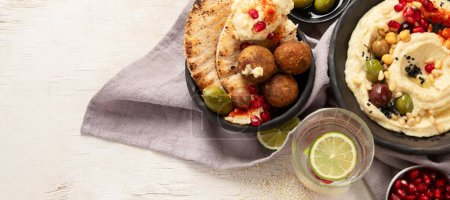Photo for Bowl of fried falafel, pita and hummus dip. Middle Eastern cuisine snack on a light background. Top view. Panorama with copy space. - Royalty Free Image