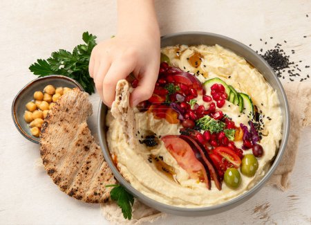 Photo for Hummus in a plate with vegetables and seesam. Dish of chickpeas, pita. A vegetarian dish on a light background. Top view. - Royalty Free Image