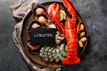 Téléchargez les photos : Assiette de fruits de mer avec homard frais, moules, huîtres comme dîner gastronomique de l'océan sur un fond sombre. Vue du dessus. - en image libre de droit