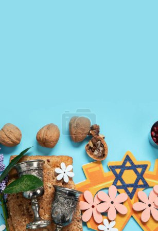 Foto de Concepto de celebración pascual. Matzah, nogal kosher rojo y flores hermosas de primavera sobre un fondo azul. Pan tradicional judío ritual. Copiar espacio. - Imagen libre de derechos