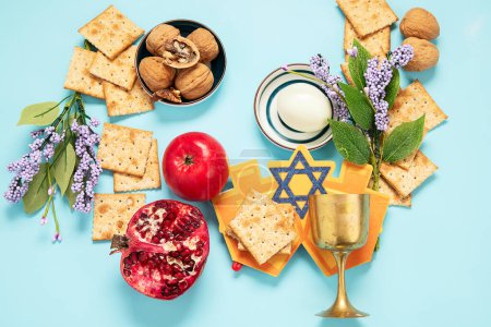 Photo for Passover celebration concept. Matzah, red kosher walnut and spring beautiful flowers on a blue background. Traditional ritual Jewish bread. - Royalty Free Image