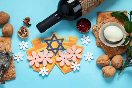 Foto de Concepto de celebración pascual. Matzah, nogal kosher rojo y flores hermosas de primavera sobre un fondo azul. Pan judío ritual tradicional. - Imagen libre de derechos