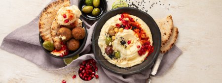 Photo for Bowl of fried falafel, pita and hummus dip. Middle Eastern cuisine snack on a light background. Top view. Panorama. - Royalty Free Image
