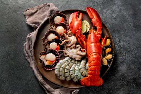 Téléchargez les photos : Assiette de fruits de mer avec homard frais, moules, huîtres comme dîner gastronomique de l'océan sur un fond sombre. Vue du dessus. - en image libre de droit