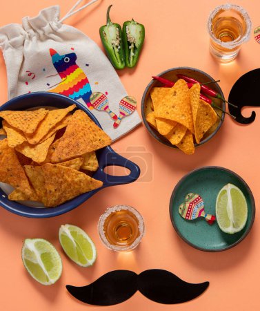 Photo for Cinco de mayo party food. Mexican holiday Cinco de mayo traditional dishes, snacks, tortilla corn chips, nachos, tacos, salsa, sauces on orange background. Top view. - Royalty Free Image