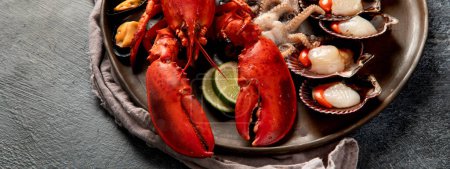 Photo for Plate of seafood with fresh lobster, mussels, oysters as an ocean gourmet dinner on a dark background. Top view. Panorama with copy space. - Royalty Free Image