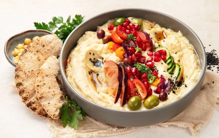 Foto de Hummus en un plato con verduras y seesam. Plato de garbanzos, pita. Un plato vegetariano sobre un fondo claro. Vista superior. - Imagen libre de derechos