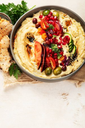 Photo for Hummus in a plate with vegetables and seesam. Dish of chickpeas, pita. A vegetarian dish on a light background. Top view. Copy space. - Royalty Free Image