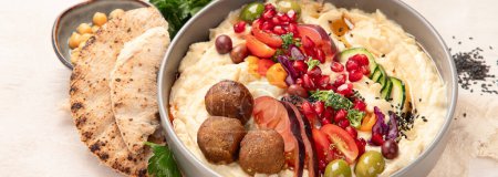Photo for Hummus in a plate with vegetables and seesam. Dish of chickpeas, pita. A vegetarian dish on a light background. Top view. Panorama. - Royalty Free Image