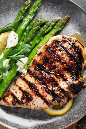 Photo for Grilled chicken breast and garnish of asparagus on a dark background. Top view. - Royalty Free Image