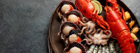 Téléchargez les photos : Assiette de fruits de mer avec homard frais, moules, huîtres comme dîner gastronomique de l'océan sur un fond sombre. Vue de dessus. Espace de copie. - en image libre de droit
