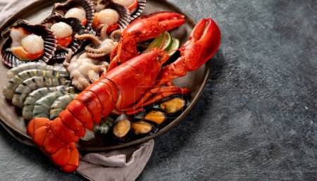 Photo for Plate of seafood with fresh lobster, mussels, oysters as an ocean gourmet dinner on a dark background. Top view. Copy space. - Royalty Free Image