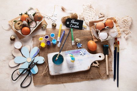 Foto de Feliz Pascua, pintando huevos. Pinturas, bolígrafos, decoraciones para colorear huevos para las vacaciones sobre un fondo blanco. Vista superior. - Imagen libre de derechos