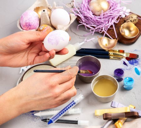 Foto de Feliz Pascua, pintando huevos. Pinturas, bolígrafos, decoraciones para colorear huevos para las vacaciones en un fondo blanco... - Imagen libre de derechos