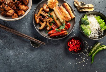 Téléchargez les photos : Tériyaki de poulet sur fond sombre avec sauces, riz, légumes et graines de sésame. De la nourriture asiatique. Vue du dessus. - en image libre de droit