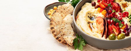 Photo for Hummus in a plate with vegetables and seesam. Dish of chickpeas, pita. A vegetarian dish on a light background. Top view. Panorama with copy space. - Royalty Free Image