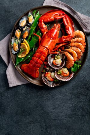 Téléchargez les photos : Grand homard rouge sur assiette avec crevettes et moules au citron, pesto à la soupe et pain. Concept de fruits de mer. Vue du dessus. - en image libre de droit