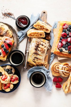 Photo for Table with various pastries and coffe cups on light backround. Top view. - Royalty Free Image