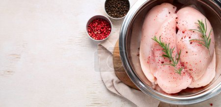 Téléchargez les photos : Poitrine de poulet crue avec romarin et poivron rouge sur fond de bois. Vue du dessus, espace de copie - en image libre de droit