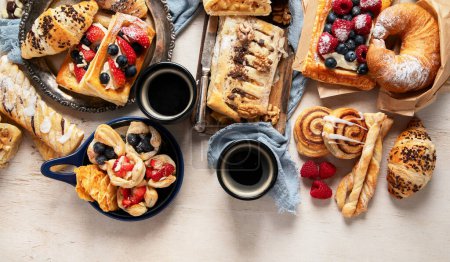 Photo for Table with various pastries and coffe cups on light backround. Top view. Copy space. - Royalty Free Image