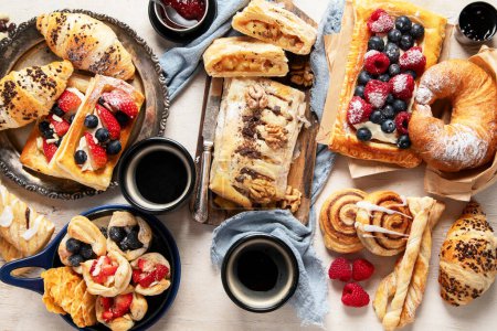 Photo for Table with various pastries and coffe cups on light backround. Top view. - Royalty Free Image