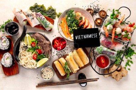 Foto de Comida asiática variada, comida vietnamita. Pho bo, fideos, rollitos de primavera, salsas. Vista superior. - Imagen libre de derechos
