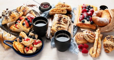 Photo for Table with various pastries and coffe cups on light backround. Top view. Panorama. - Royalty Free Image