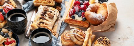 Photo for Table with various pastries and coffe cups on light backround. Top view. Panorama with copy space. - Royalty Free Image