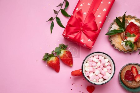 Foto de Fondo rosa festivo con cupcake, fresas, chocolates, bebida caliente. Celebración de cumpleaños. Vista superior, espacio de copia - Imagen libre de derechos