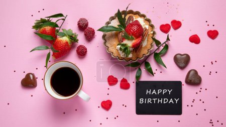 Foto de Fondo rosa festivo con cupcake, fresas, chocolates, bebida caliente. Celebración de cumpleaños. Vista superior - Imagen libre de derechos