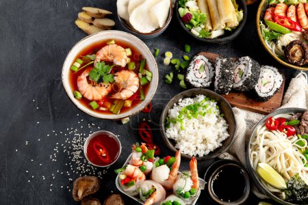 Photo for Traditional Asian food table. Spring roll, rice, shrimp, sushi, vegetables, meat on dark background. Top view - Royalty Free Image