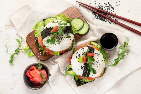 Téléchargez les photos : Nourriture hybride moderne. Burger sushi au saumon, riz blanc, avocat, concombre. Vue du dessus - en image libre de droit